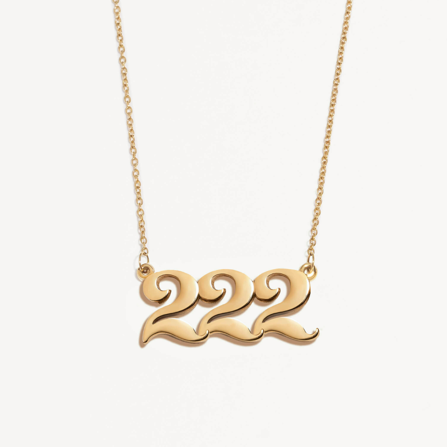 Gold necklace with '222' design on a white background
