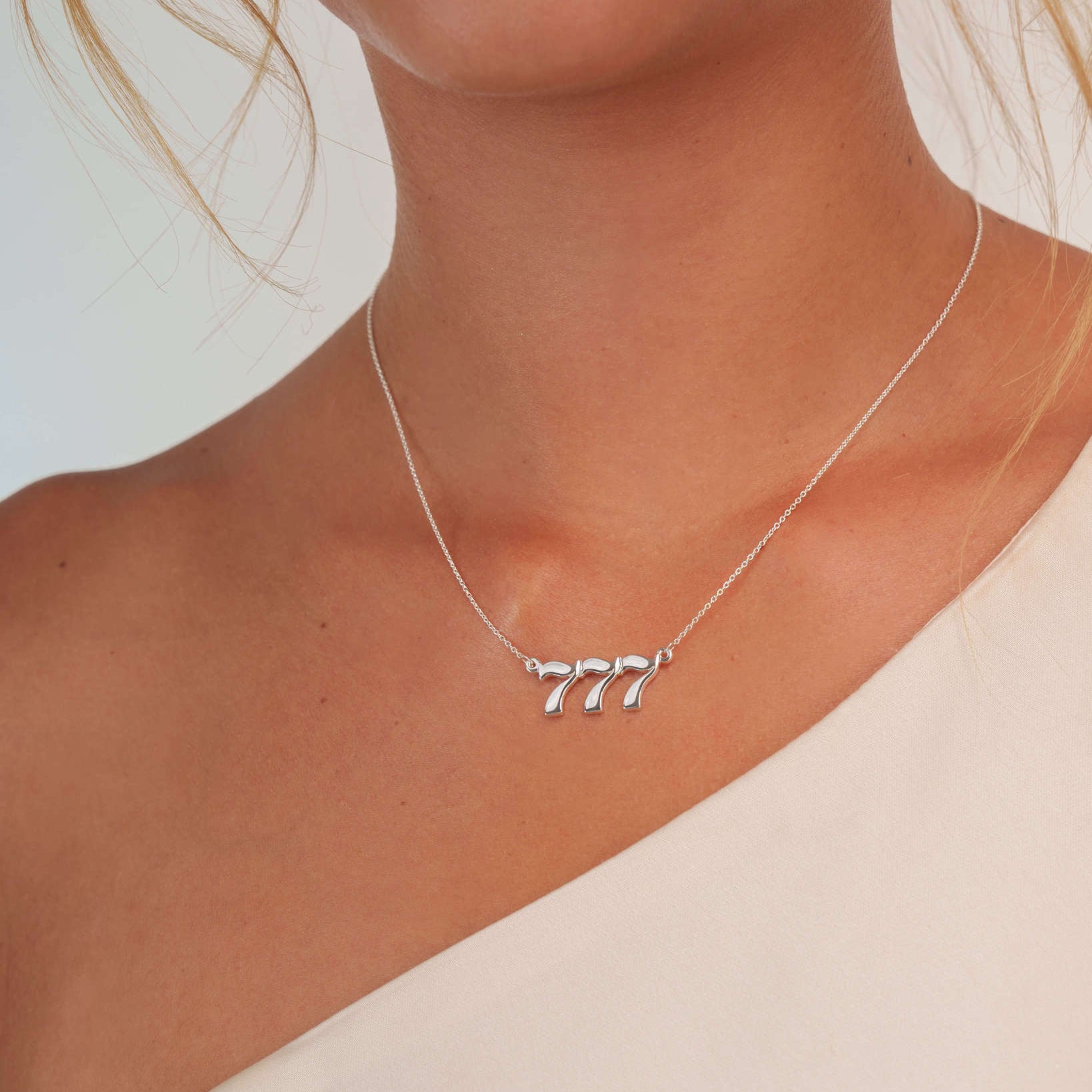 777 silver necklace closeup on model