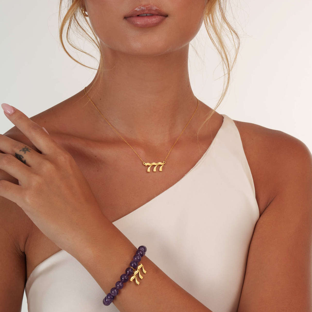 woman wearing gold 777 necklace with matching amethyst 777 charm bracelet