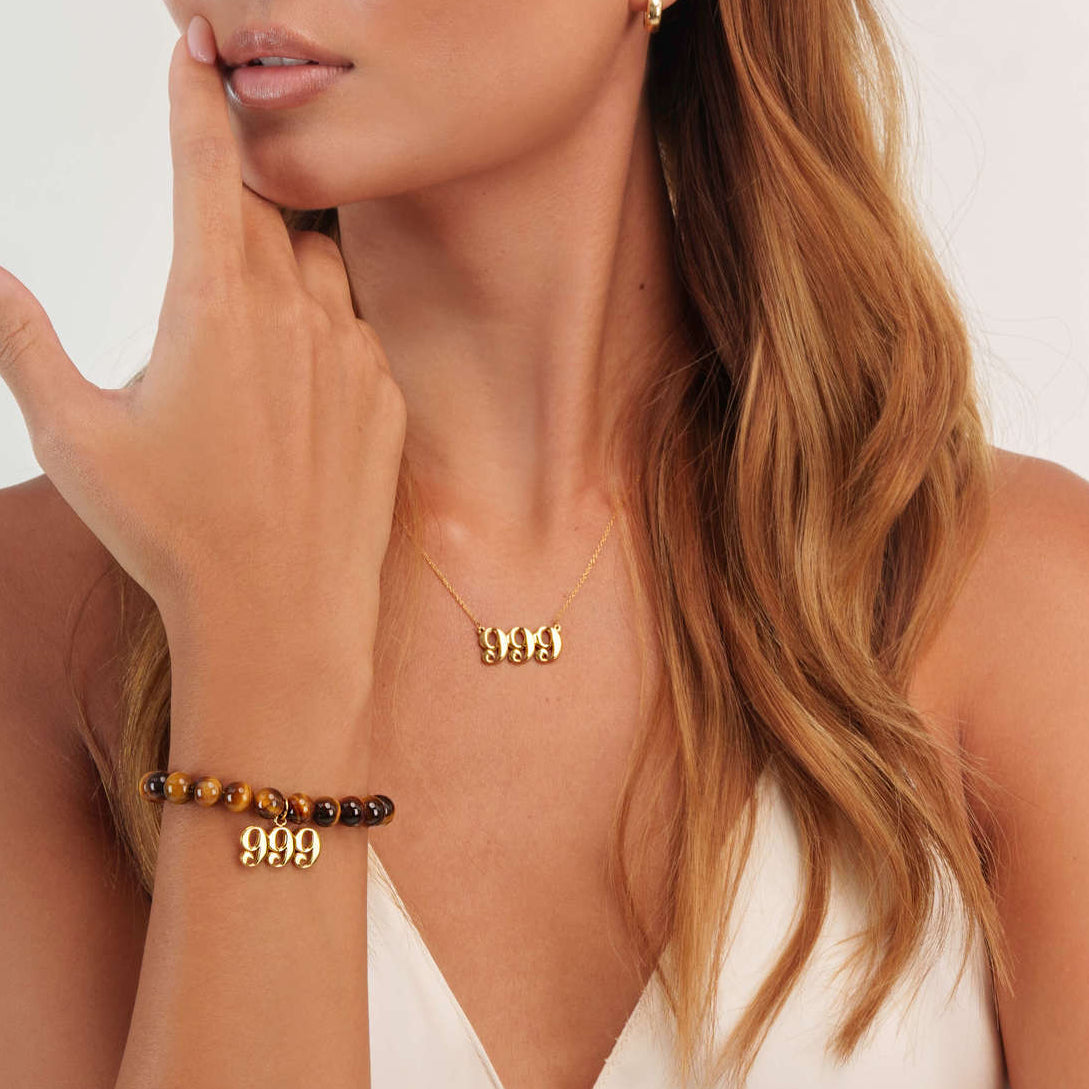 woman wearing gold 999 necklace with matching gold 999 charm bracelet with tigers eye gemstones.