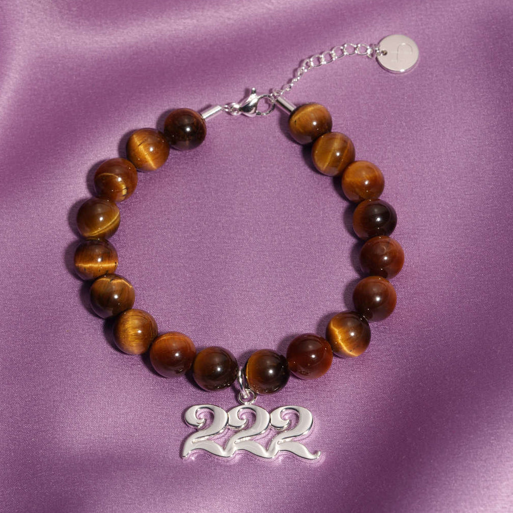 222 Silver charm on beaded Tigers Eye bracelet laying on silk
