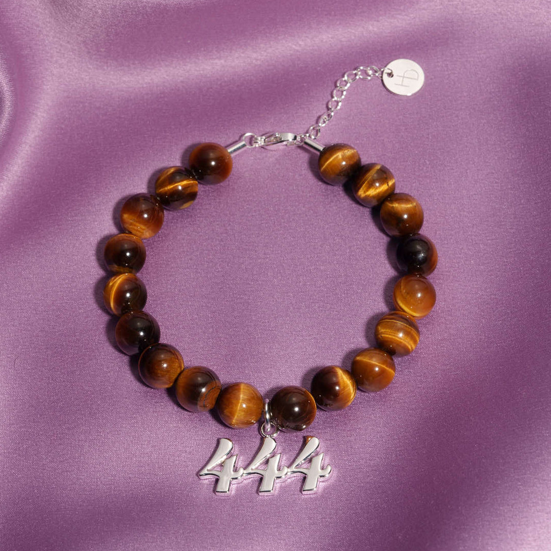 444 Silver charm on beaded Tigers Eye bracelet laying on silk
