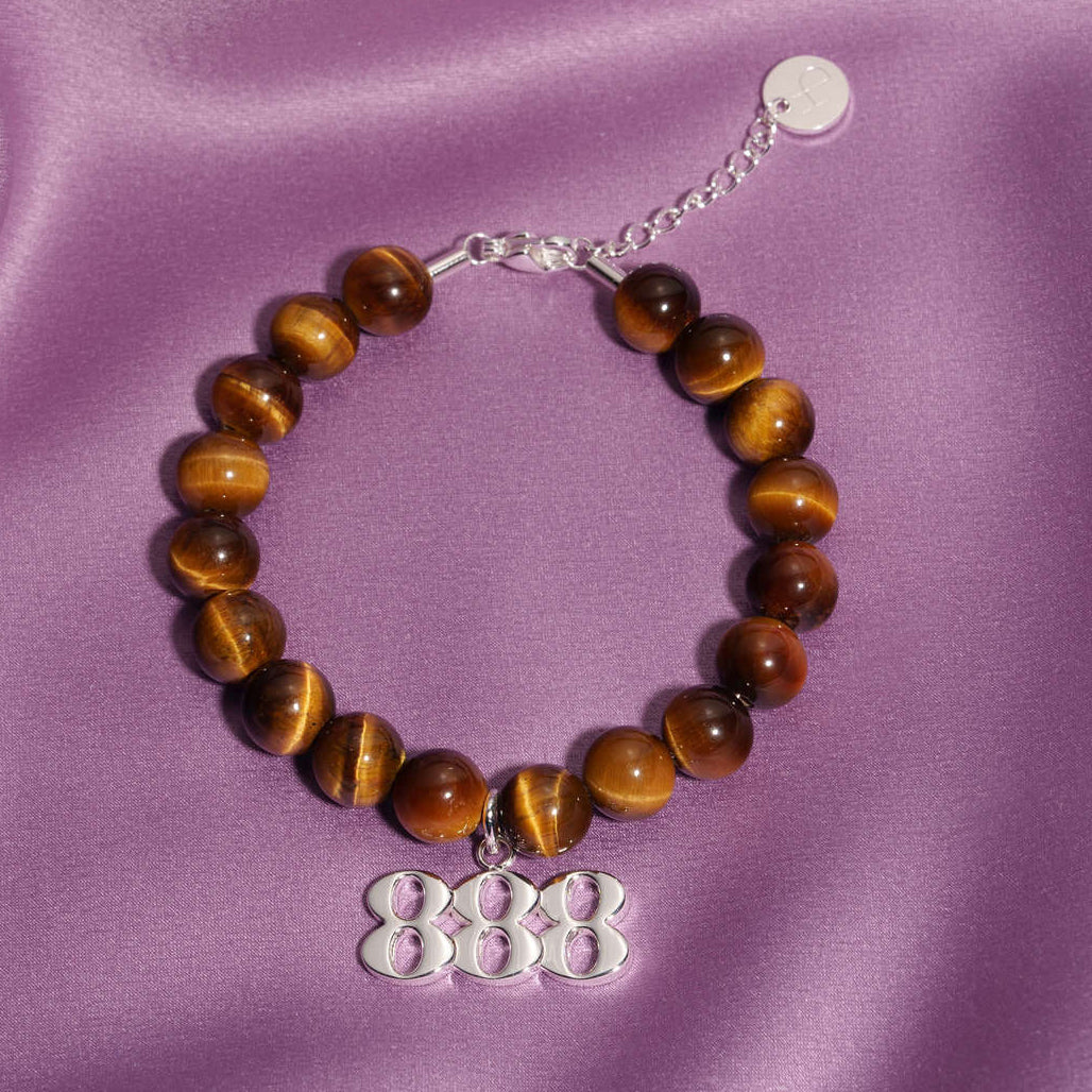 888 Silver charm on beaded Tigers Eye bracelet laying on silk
