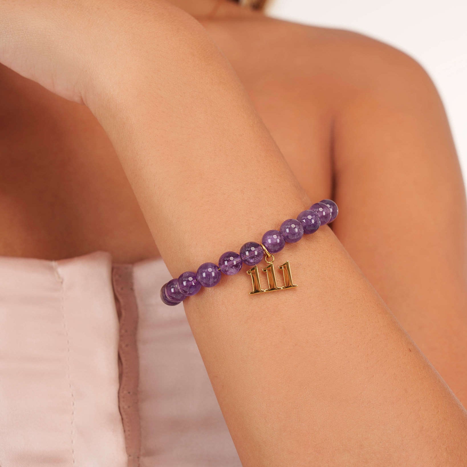 High quality purple amethyst beads with dangling 111 gold charm on wrist
