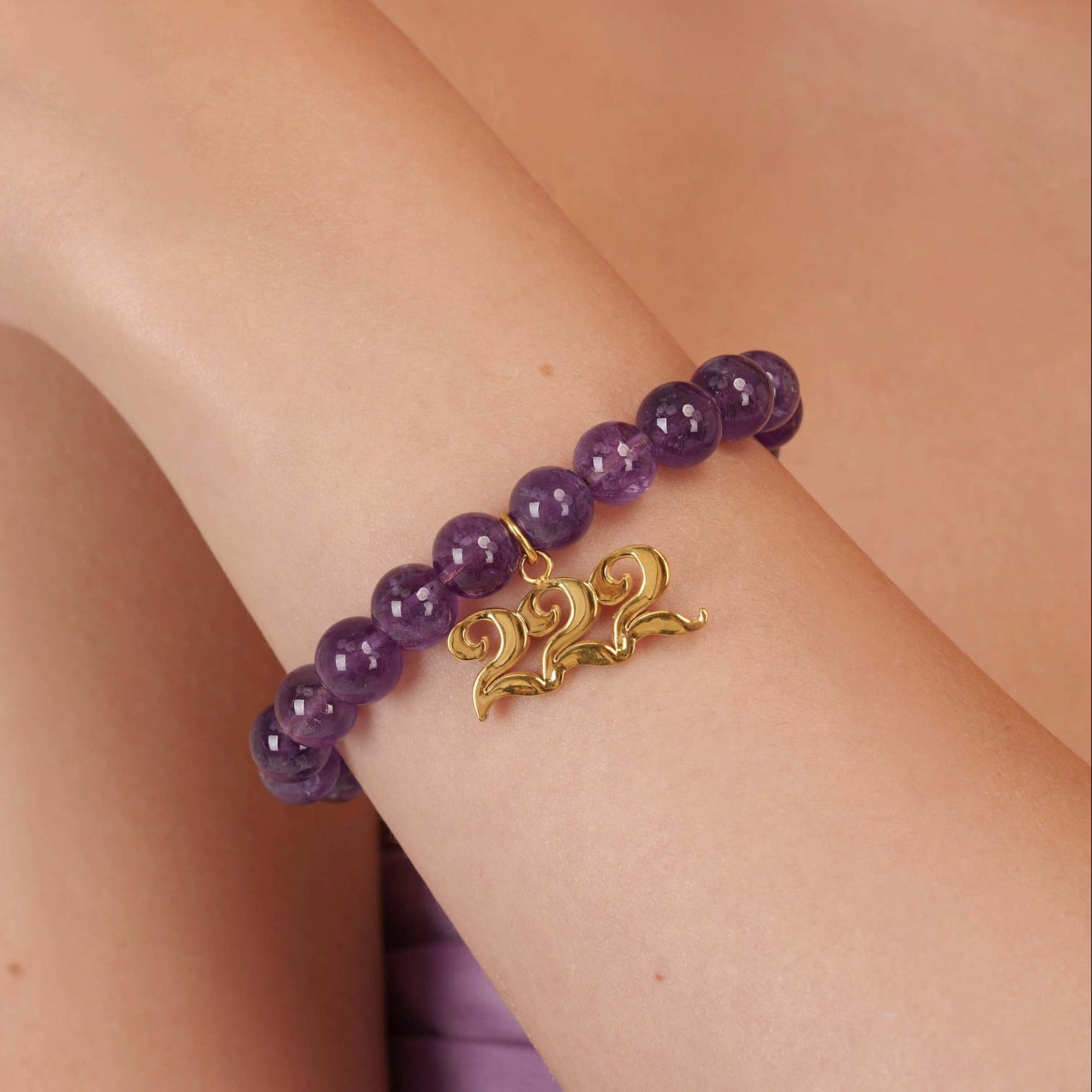 High quality purple amethyst beads with dangling 222 gold charm on wrist
