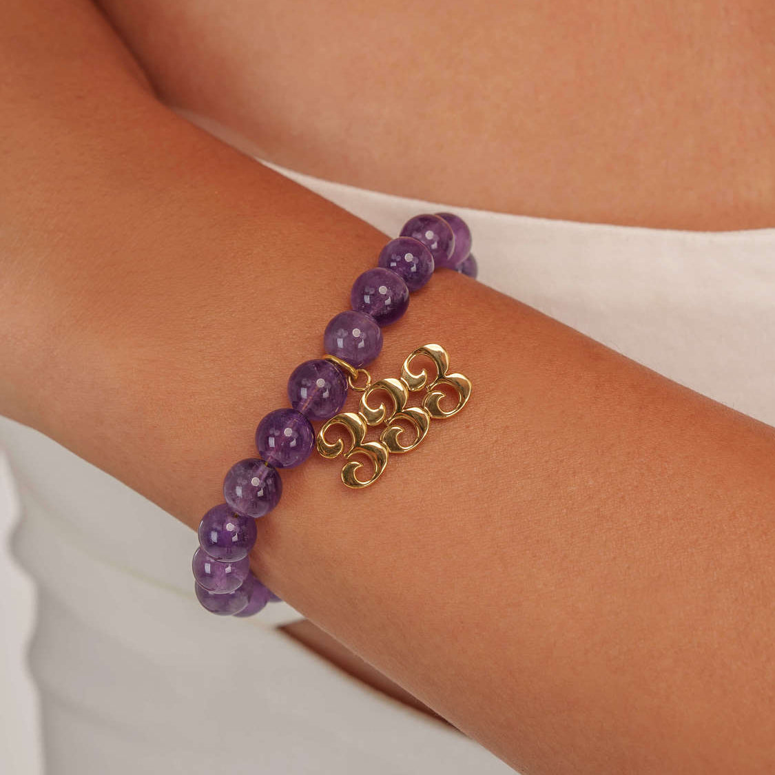 High quality purple amethyst beads with dangling 333 gold charm on wrist
